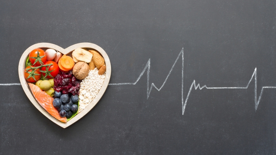 A heart filled with different healthy foods against gray backdrop.